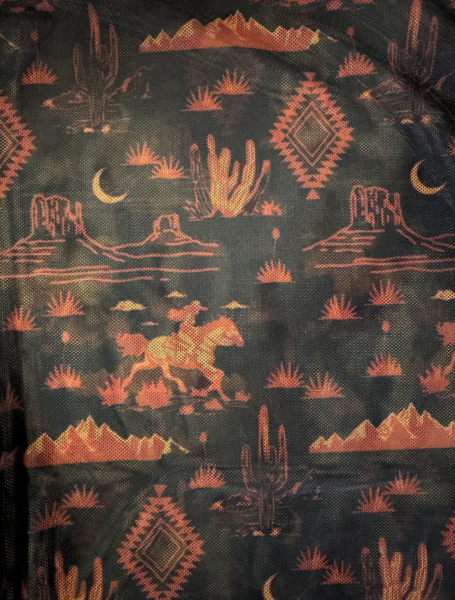 Close-up of the desert print showing cactus, mesas, crescent moons, and a rider on horseback in rust on black mesh