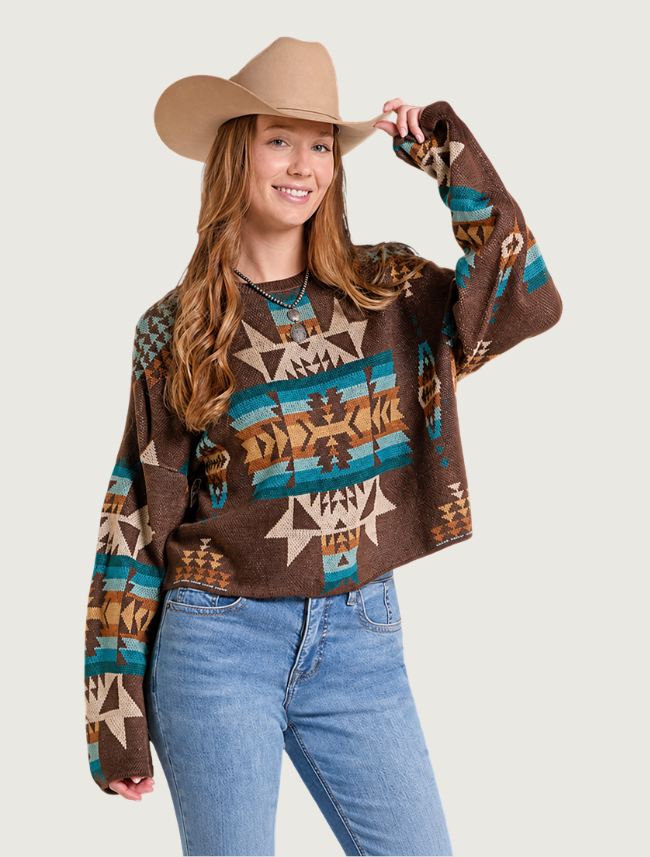 Model in a cowboy hat wearing the cropped sweater with high-rise jeans, three-quarter view