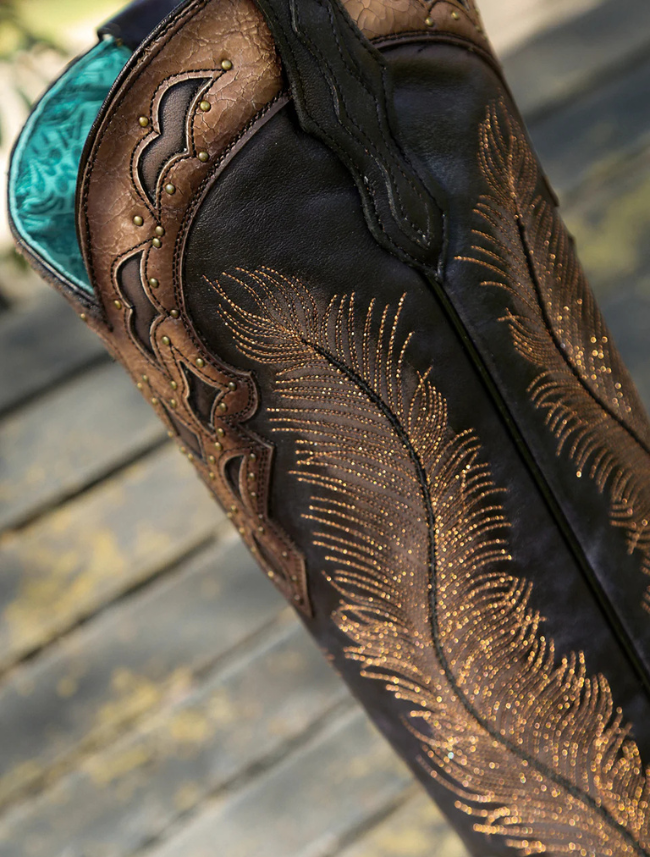 Close-up of a leather boot with intricate gold embroidery on a wooden surface.