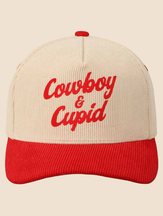 Close up of cowboy and cupid trucker hat for a product photosgraphy with red brim and cream hat