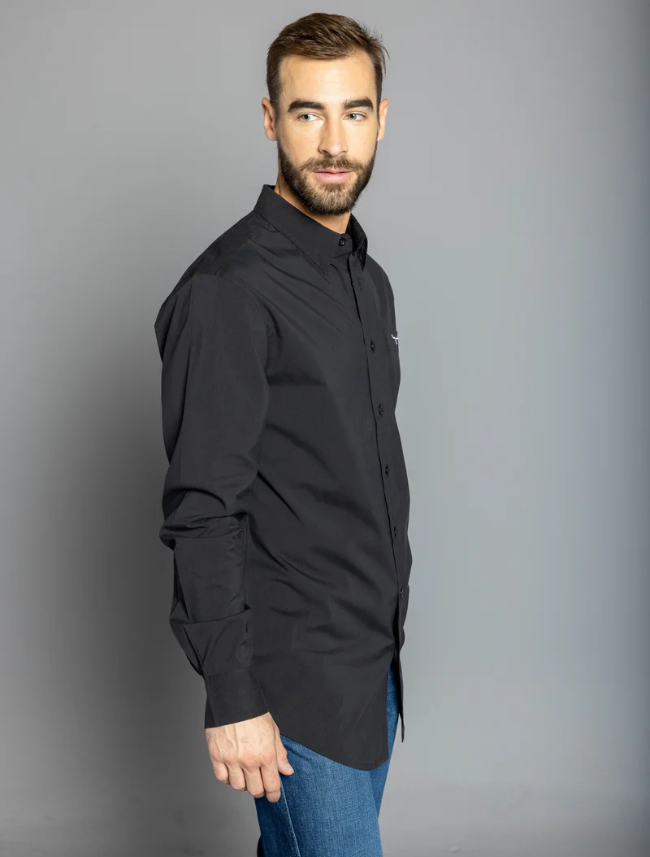 A man wearing a long-sleeved black dress shirt with a single chest pocket and a small embroidered logo on the chest area. The shirt has a button-up front and is modeled in a standing position against a gray background.