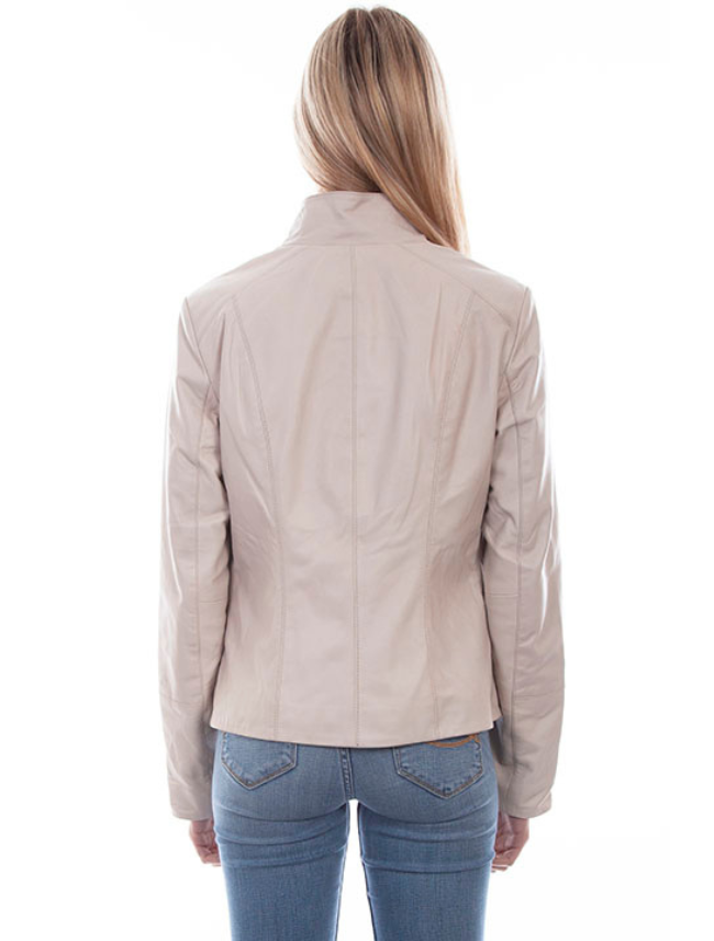 A woman wearing a beige zip front leather jacket with a stand up collar and paired with blue jeans.