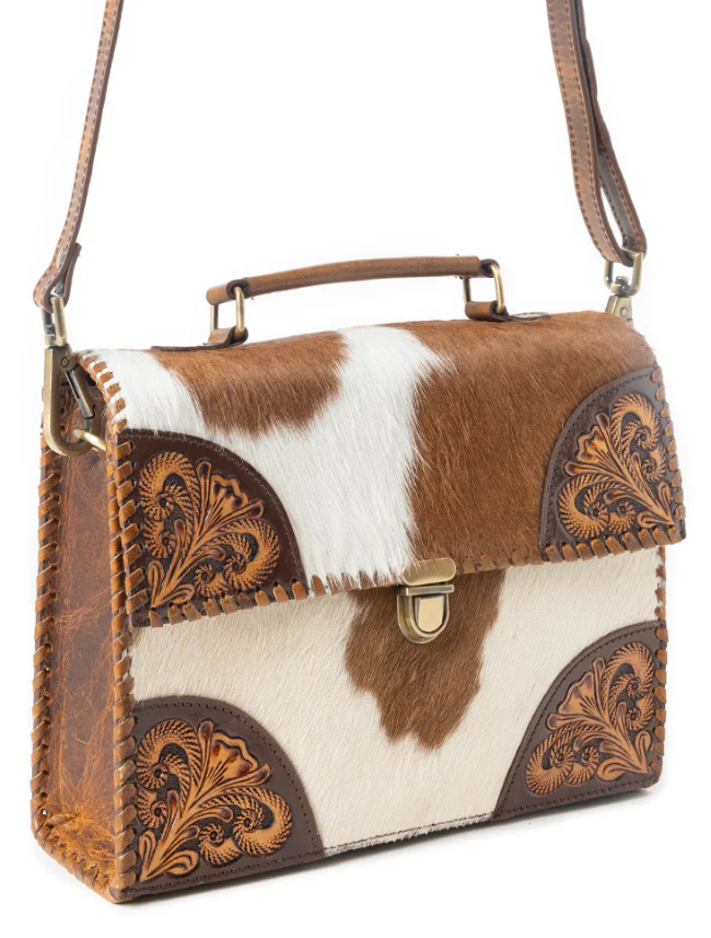 Brown and white cowhide handbag with decorative leather accents on a white background