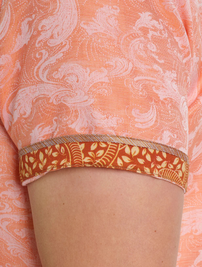 Close-up of sleeve on a person wearing a patterned orange shirt with visible patterned inner fabric.