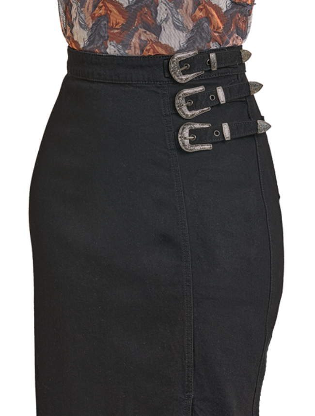 Woman wearing a black skirt with silver buckles worn over a patterned top on a white background