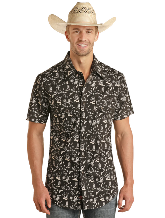 A man wearing a black short sleeve snap shirt with a tattoo print, paired with a straw hat and blue jeans.