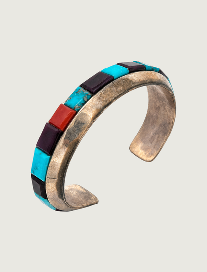 Angled view of Michael Dukepoo sterling silver inlay cuff bracelet showing turquoise, coral, and sugilite along the band