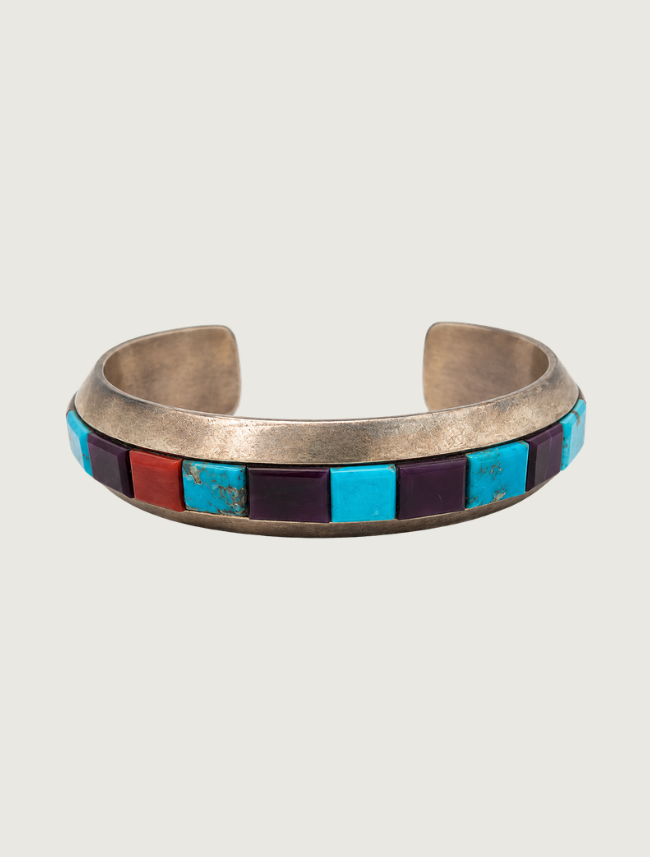 Sterling silver cuff bracelet by Michael Dukepoo with a row of inlaid turquoise, coral, and sugilite stones