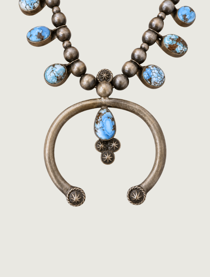 Detail of Donovan Skeet squash blossom naja pendant with Golden Hills turquoise and star stamp accents