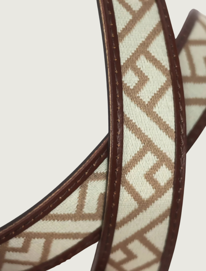 Detail of the Trailhead belt strap looped to highlight the cream-and-tan geometric weave and stitched brown leather edges