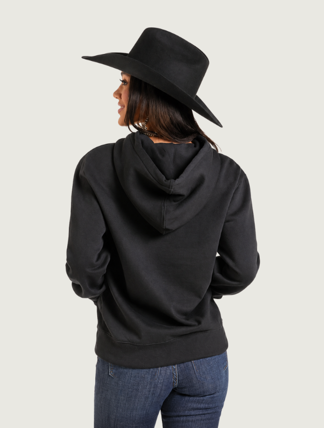 Back view of the plain black hoodie with the hood down, worn by a woman in a cowboy hat
