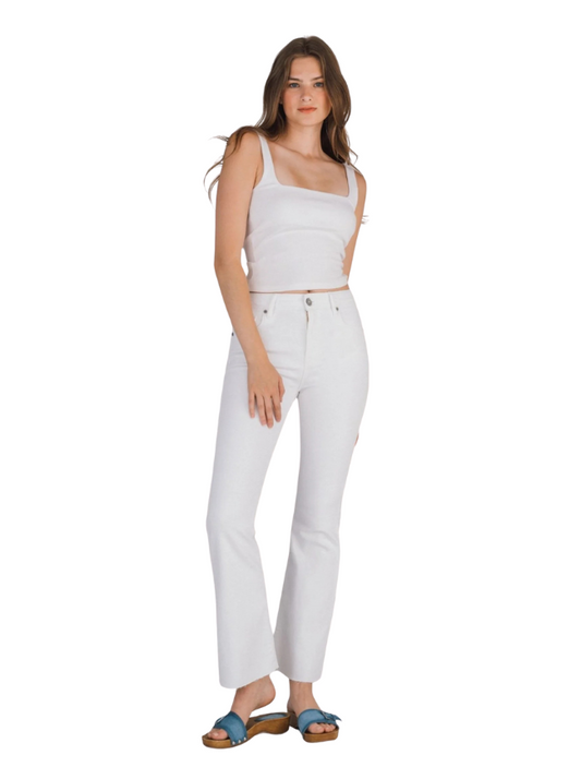Woman wearing a white tank top and white pants on a white background
