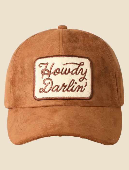 uede trucker hat with “Howdy Darlin’” embroidered in cream thread on a soft tan front panel.