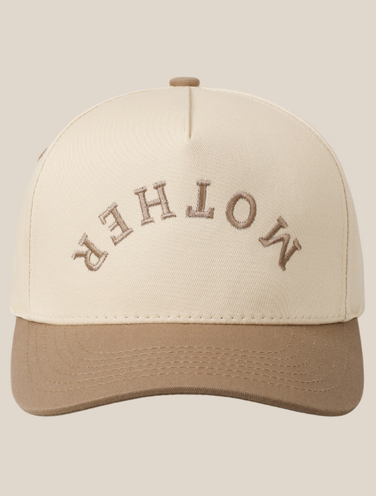 Cream and tan trucker hat featuring the phrase “Mother” embroidered upside down in bold lettering across the front.