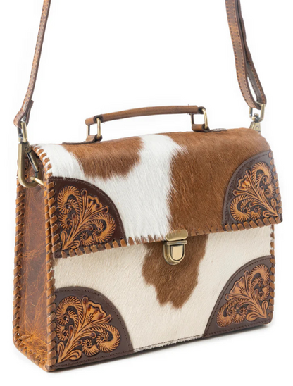 Brown and white cowhide handbag with decorative leather accents on a white background