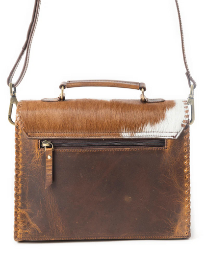 Brown leather handbag with a white cowhide patch on a white background