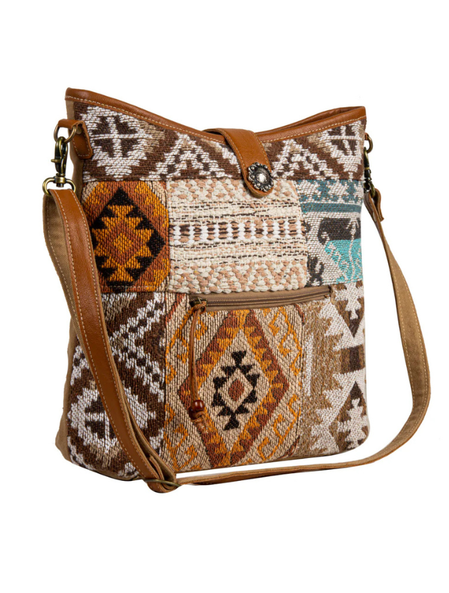 Patterned shoulder bag with brown leather accents on a white background