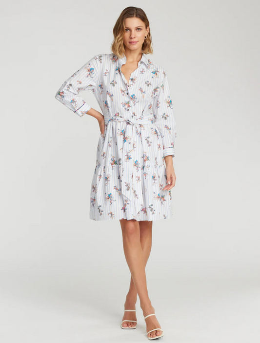 A woman modeling a Robert Graham Paloma Dress with a striped floral print. The dress features a point collar, buttoned waist, and a tiered skirt.