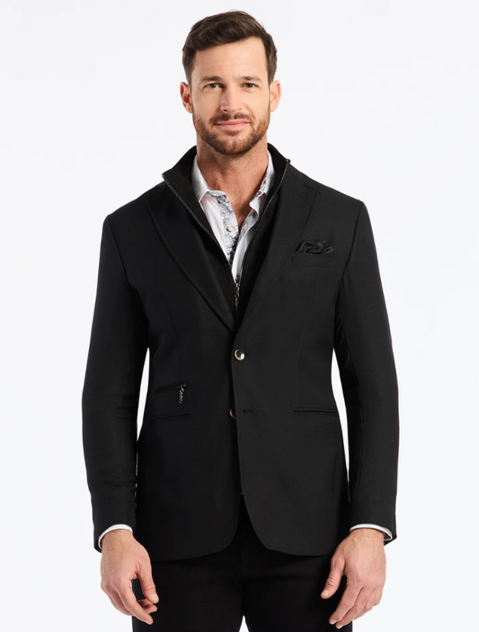 Man wearing a black blazer over a patterned shirt on a white background