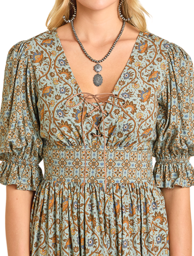 Woman wearing a green mixed print dress with a silver western necklace on a white background