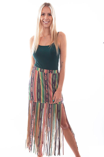 A woman wearing a multicolored serape print fringe skirt with a green tank top.