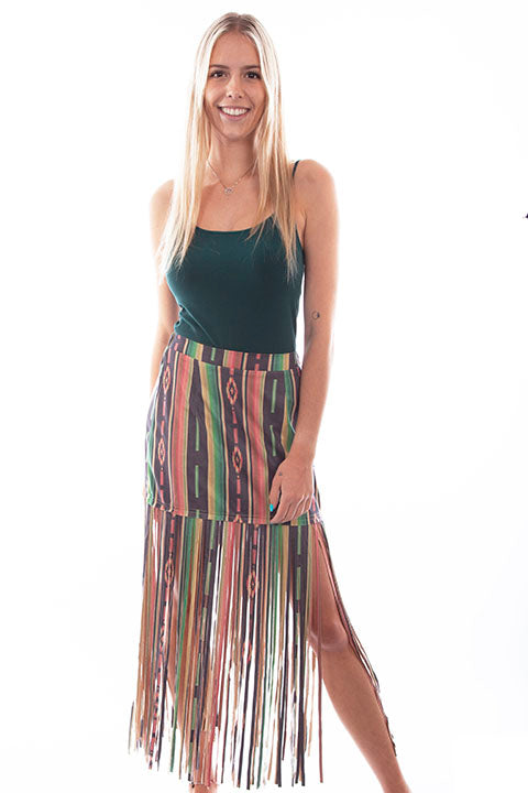 A woman wearing a multicolored serape print fringe skirt with a green tank top.