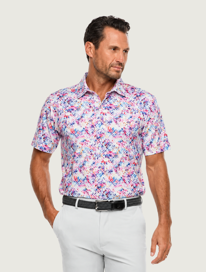 Man wearing Robert Graham Pink Sands geo-floral golf polo with white pants, front view